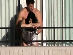 couple pokes on hotel balcony