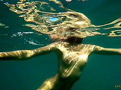 Nude model swims on a public beach in Russia.