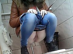 Slender girl in very tight blue denim filmed in the toilet room