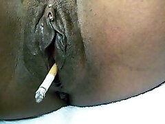 Good-sized black shiny pussy smoking a cigarette on webcam