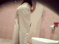 A woman wearing white jeans is bandicam sammi tye in the public toilet