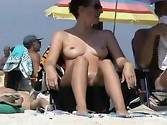 Big breasted coquette sunbathing on a tv host live beach