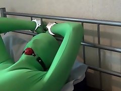 tied up and ball gagged in green tube at last zentai bodysuit