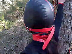 Tied up to a tree, outdoors in sexy clothes, ball gagged
