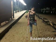 Amputee woman with crutches on the beach