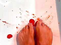 Perfect sexy brown feet squish tomatoes in bathtub