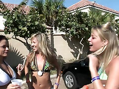 Three slim girls in bikinis and miniskirts have fun in the street